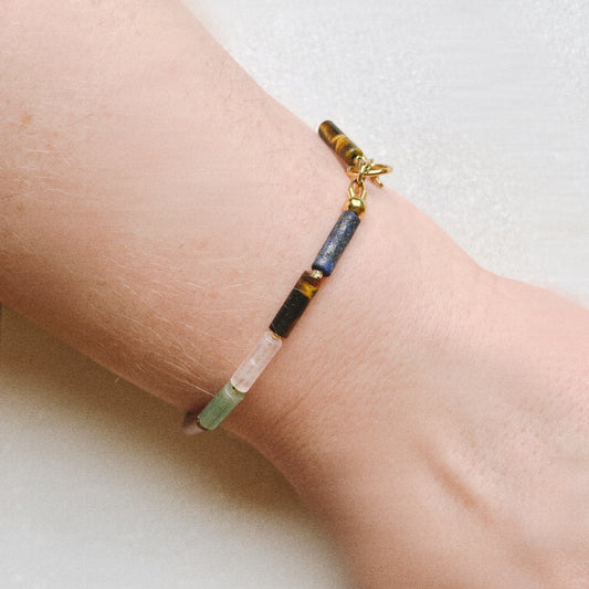 Bracelet with multicolored stone beads on a wrist against a neutral background