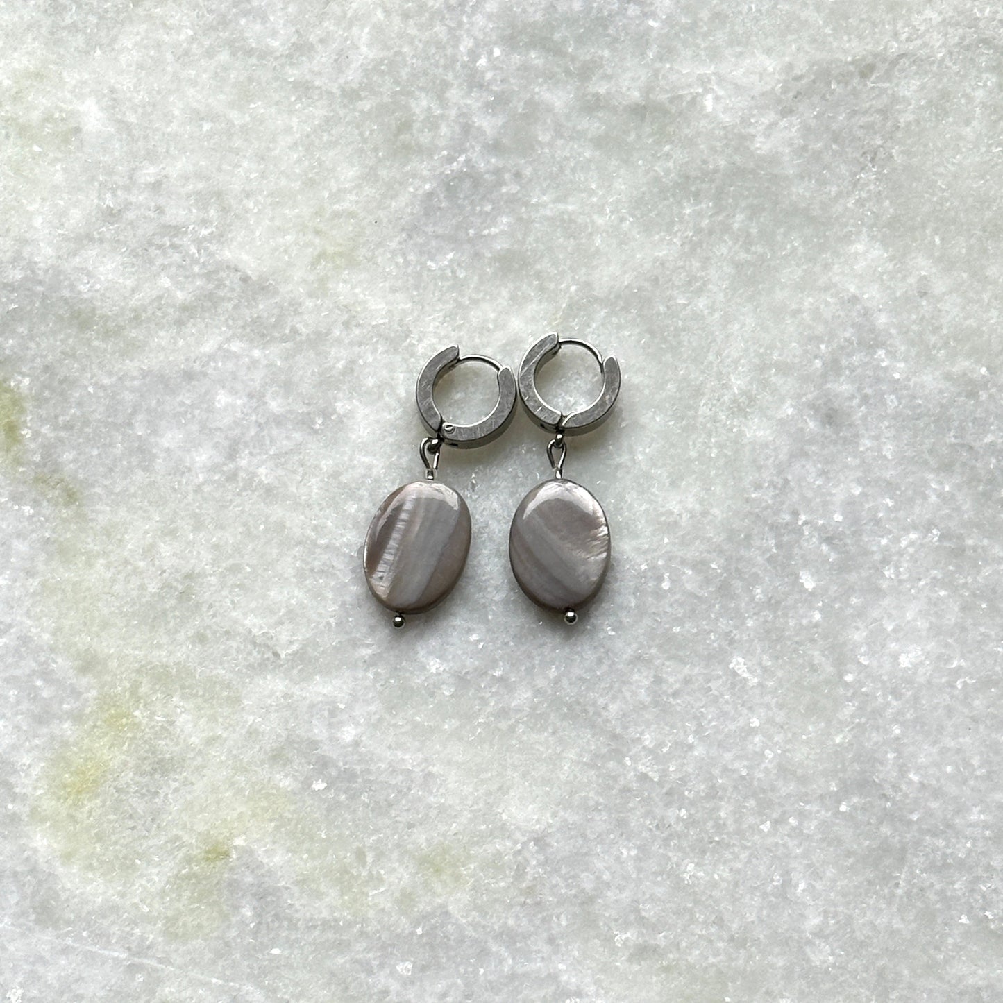A pair of earrings in silver features mother-of-pearl pendants.