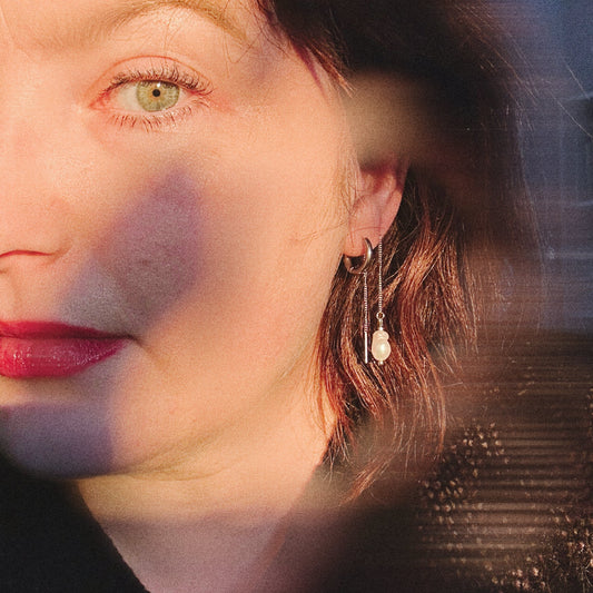Close-up of a woman's face with a pearly earring and a blurred background