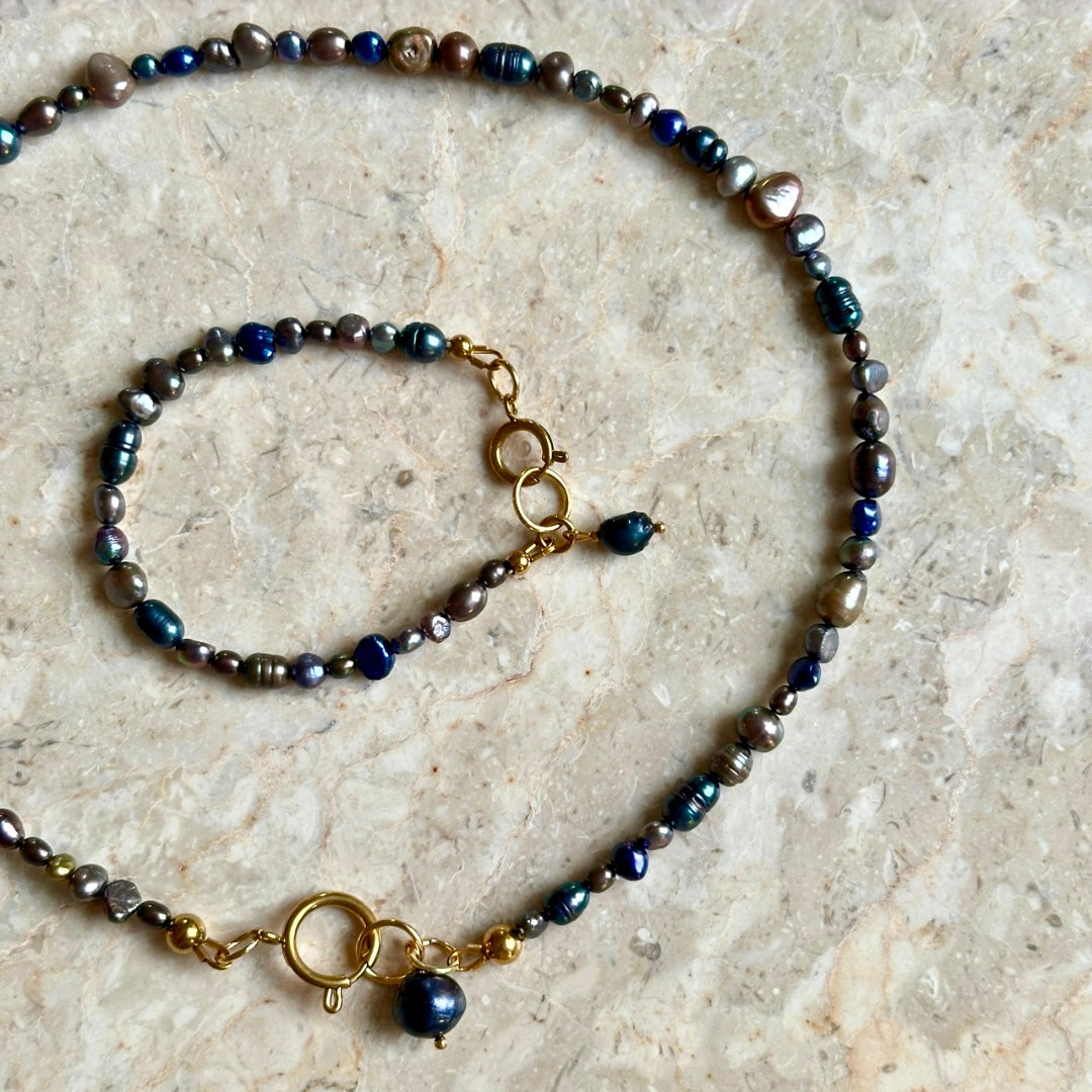 Necklace with blue and gold beads on a beige stone surface