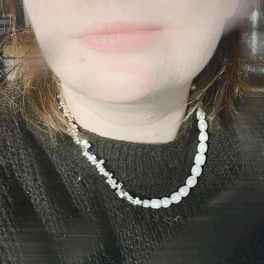 Close-up of a person wearing a pearl necklace with a blurred background