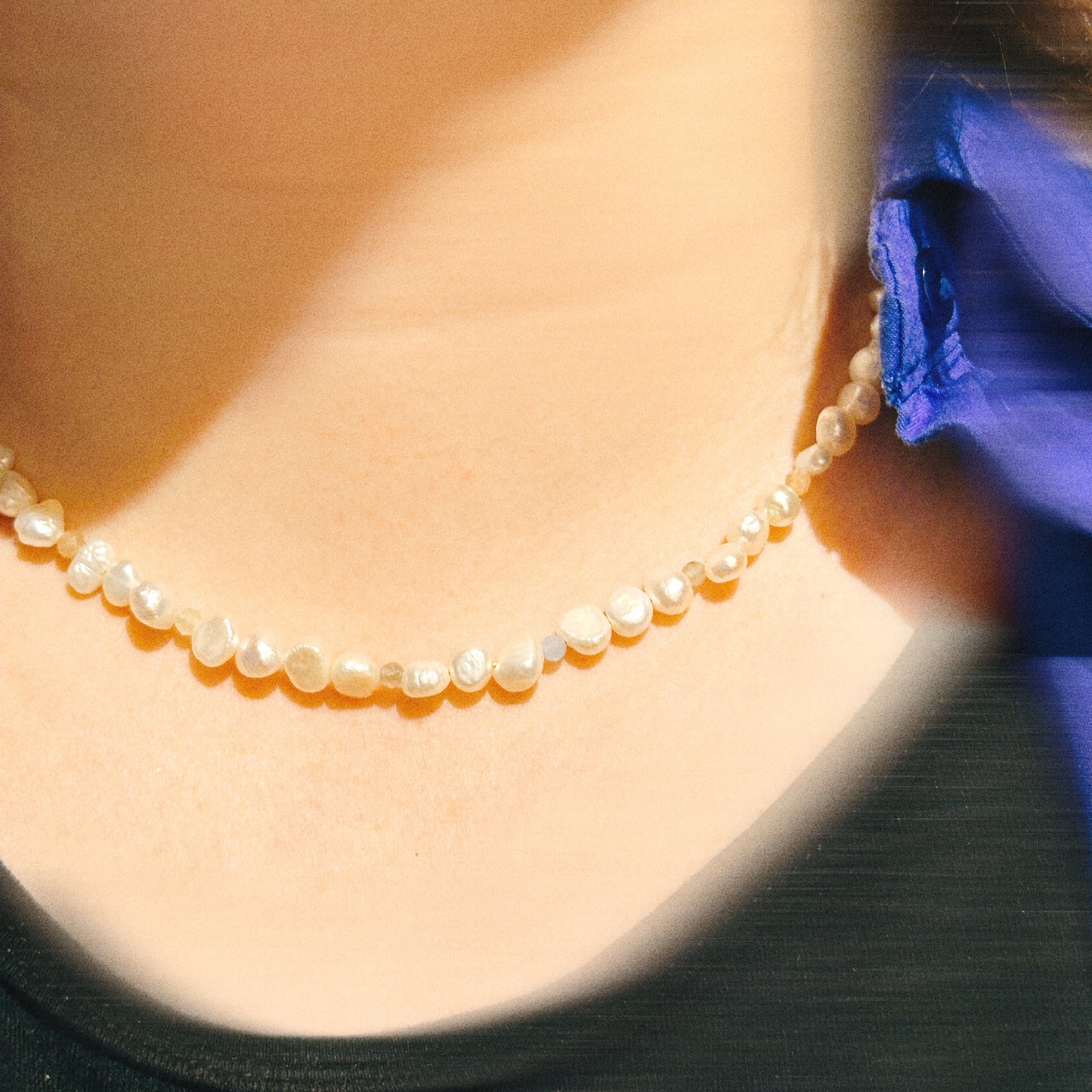 Pearl necklace worn by a person with a blurred background