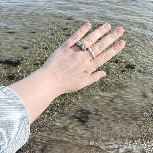 Hand with rings in front of a body of water
