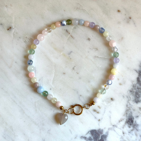 Handmade beaded necklace with colourful stones and a heart pendant made of agate on a marble surface