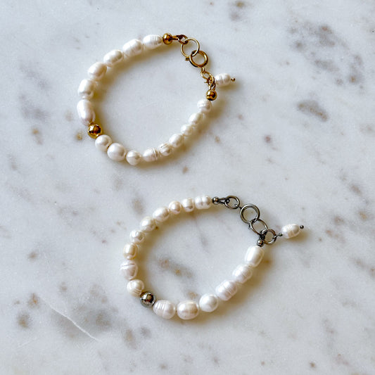 Two handmade pearl bracelets with gold and silver bead on a marble surface