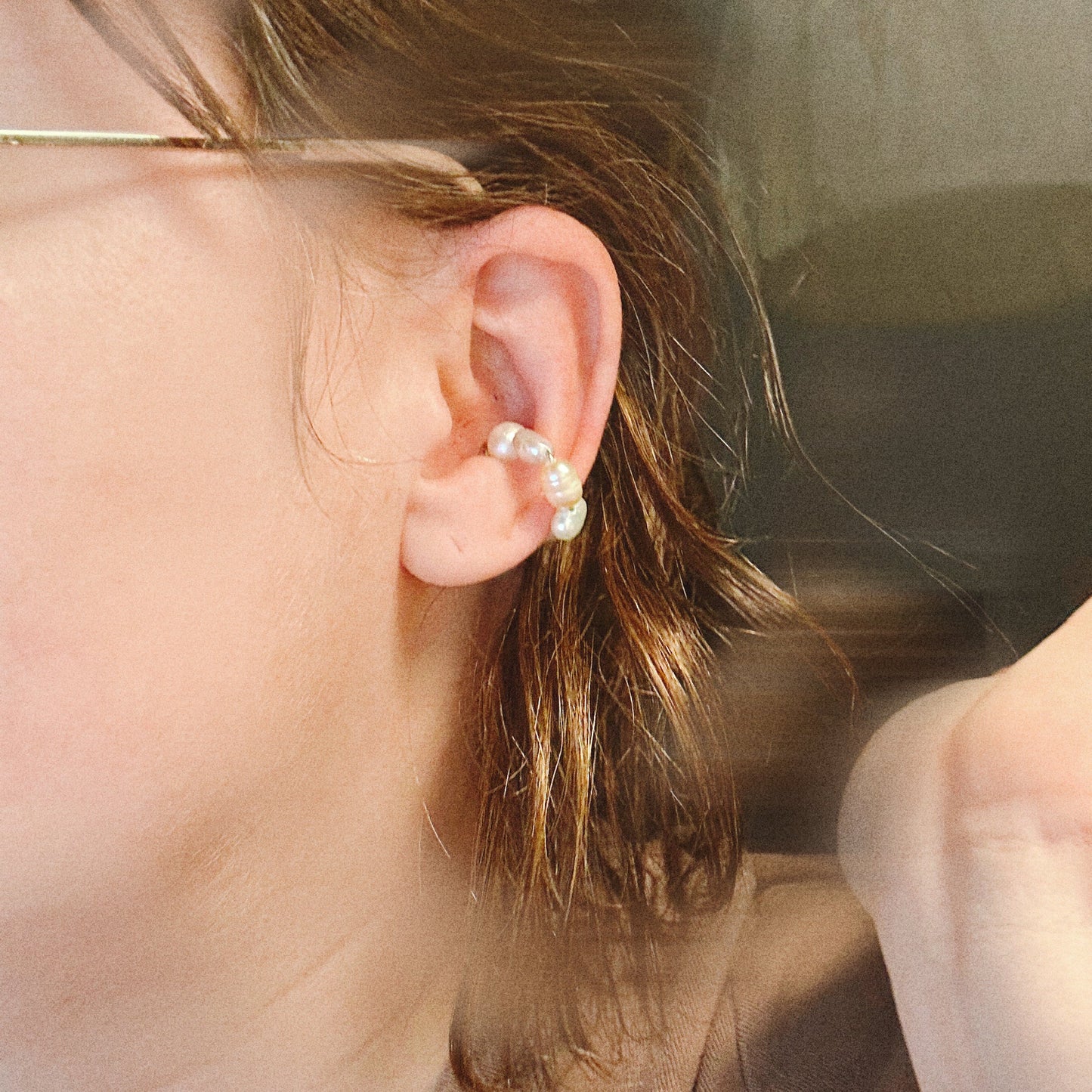 Close-up of an ear wearing a pearl earring with a blurred background