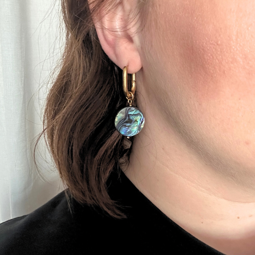 handmade earrings of abalone shell hanging in an ear