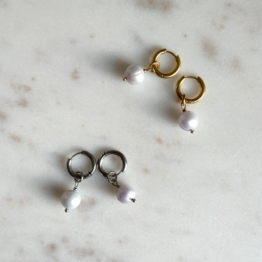 Pair of blue pearl earrings on a marble surface