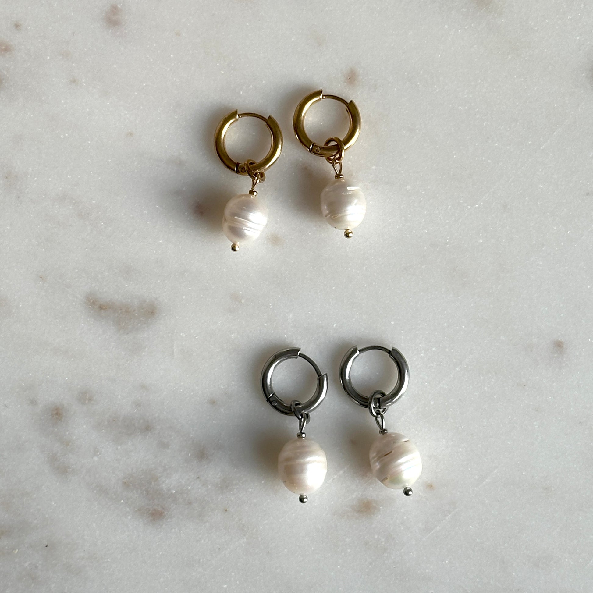 Pair of hoop earrings with pearl drops on a light gray surface