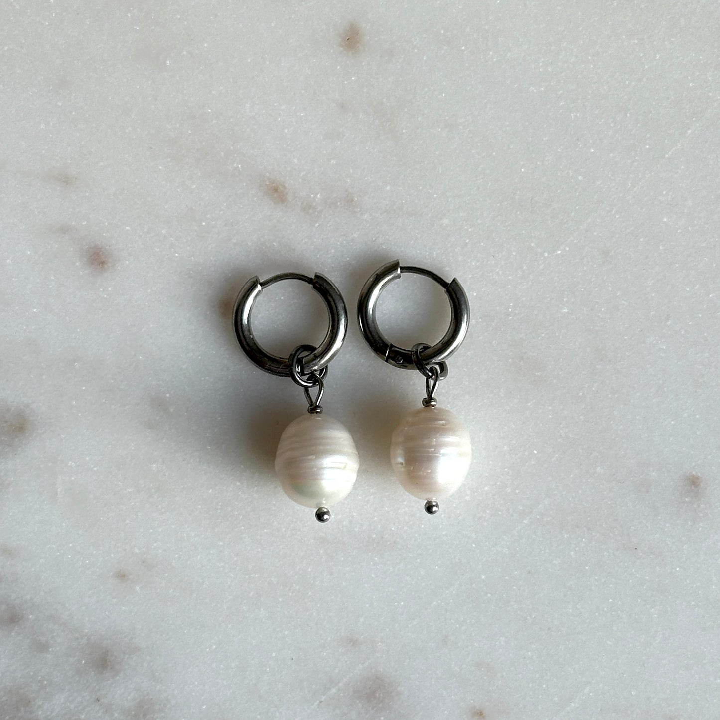 Pair of hoop earrings with pearl drops on a light gray background