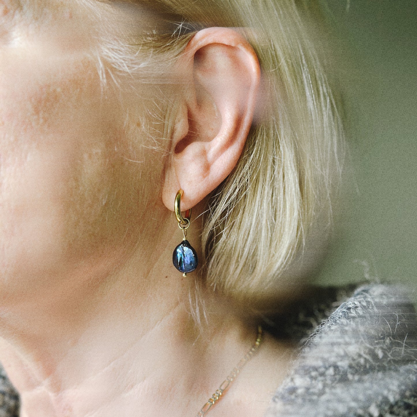 Close-up of a person wearing a blue teardrop earring.
