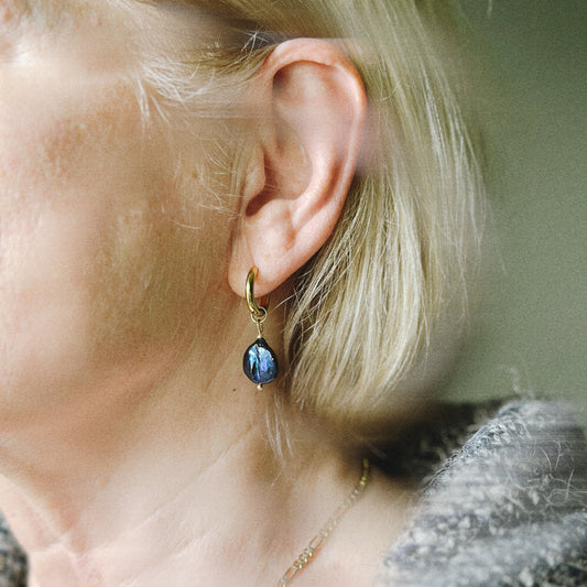Close-up of a person wearing a blue teardrop earring.
