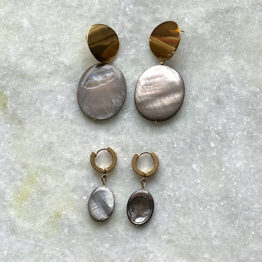 Two pairs of earrings, one larger and one smaller, with the smaller ones in silver and the larger ones in gold. Both pairs feature mother-of-pearl pendants.
