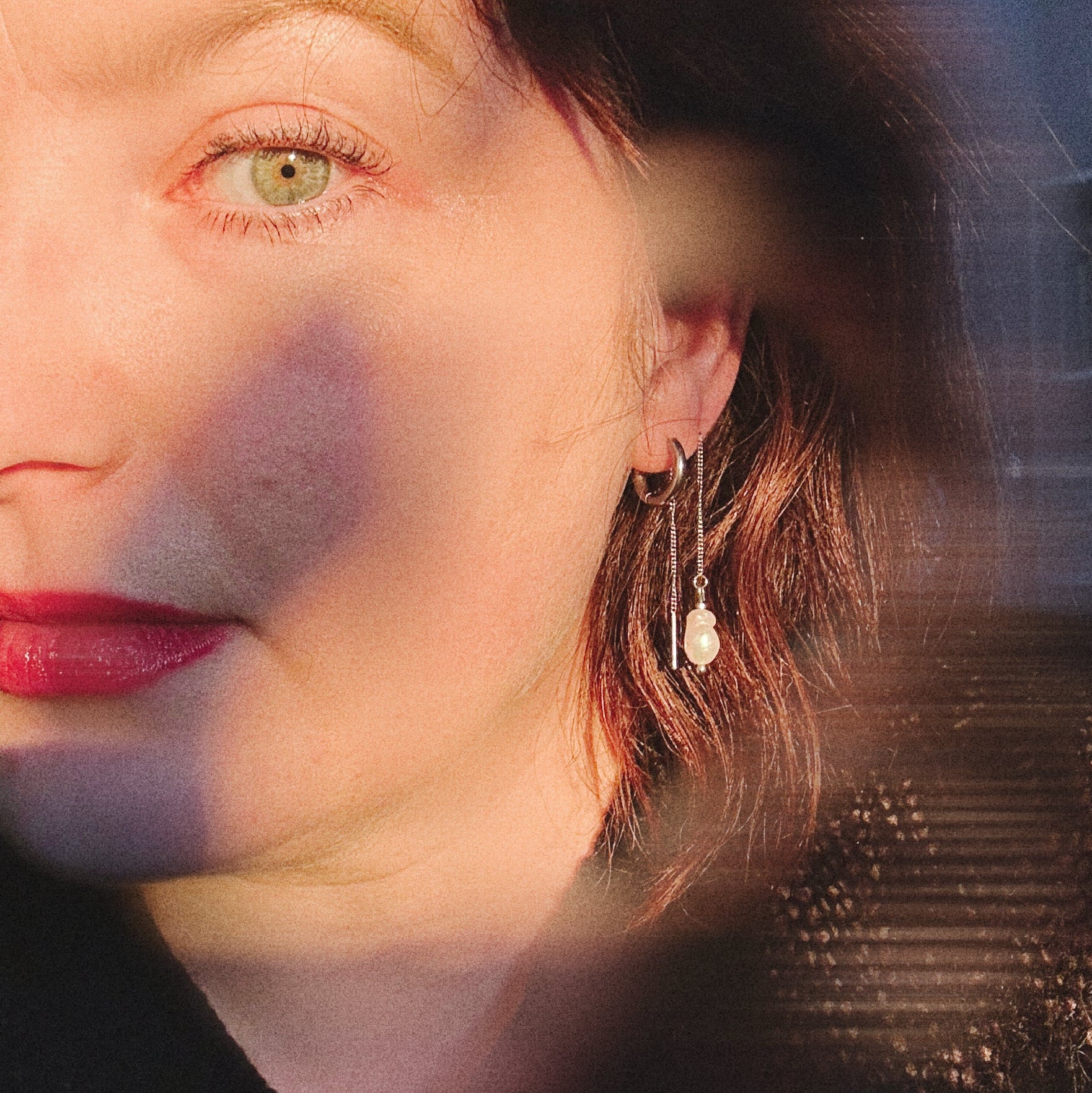 Close-up of a woman's face with a pearly earring and a blurred background