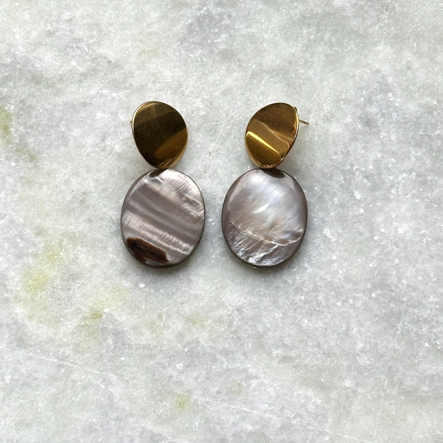 A pair of earrings in gold finish, that feature mother-of-pearl pendants.