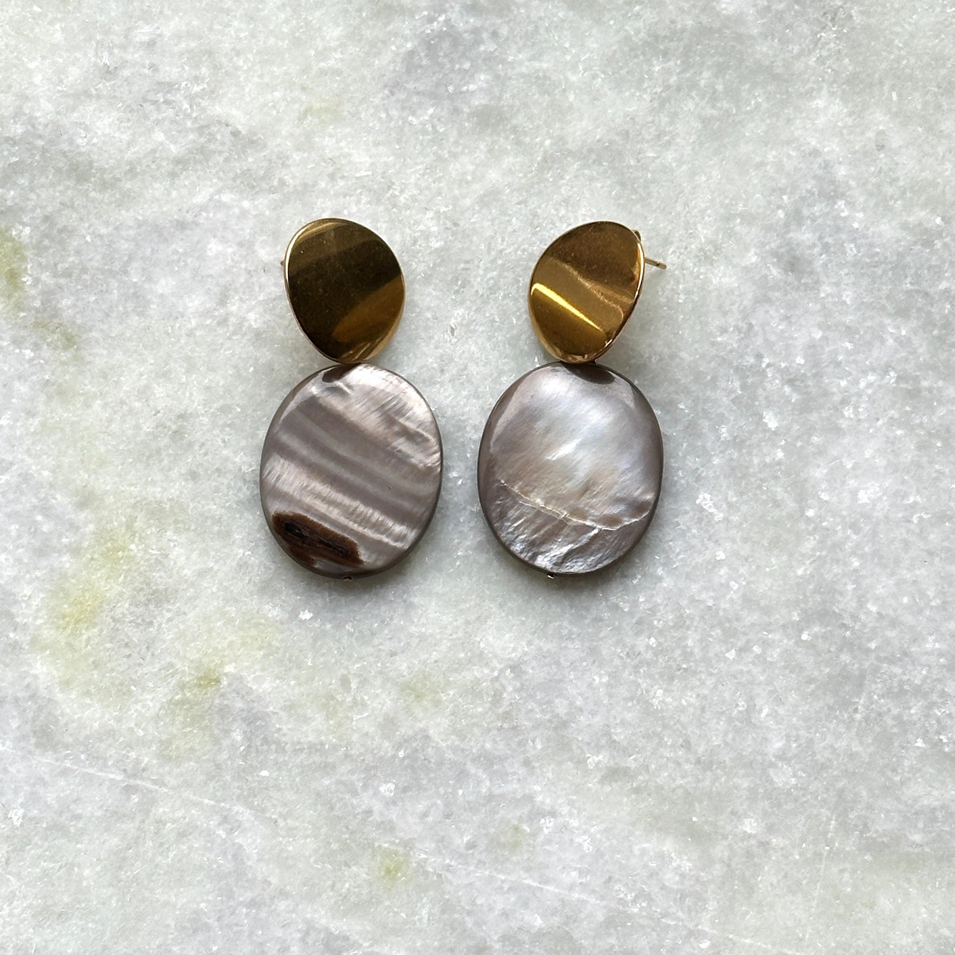 A pair of earrings in gold finish, that feature mother-of-pearl pendants.
