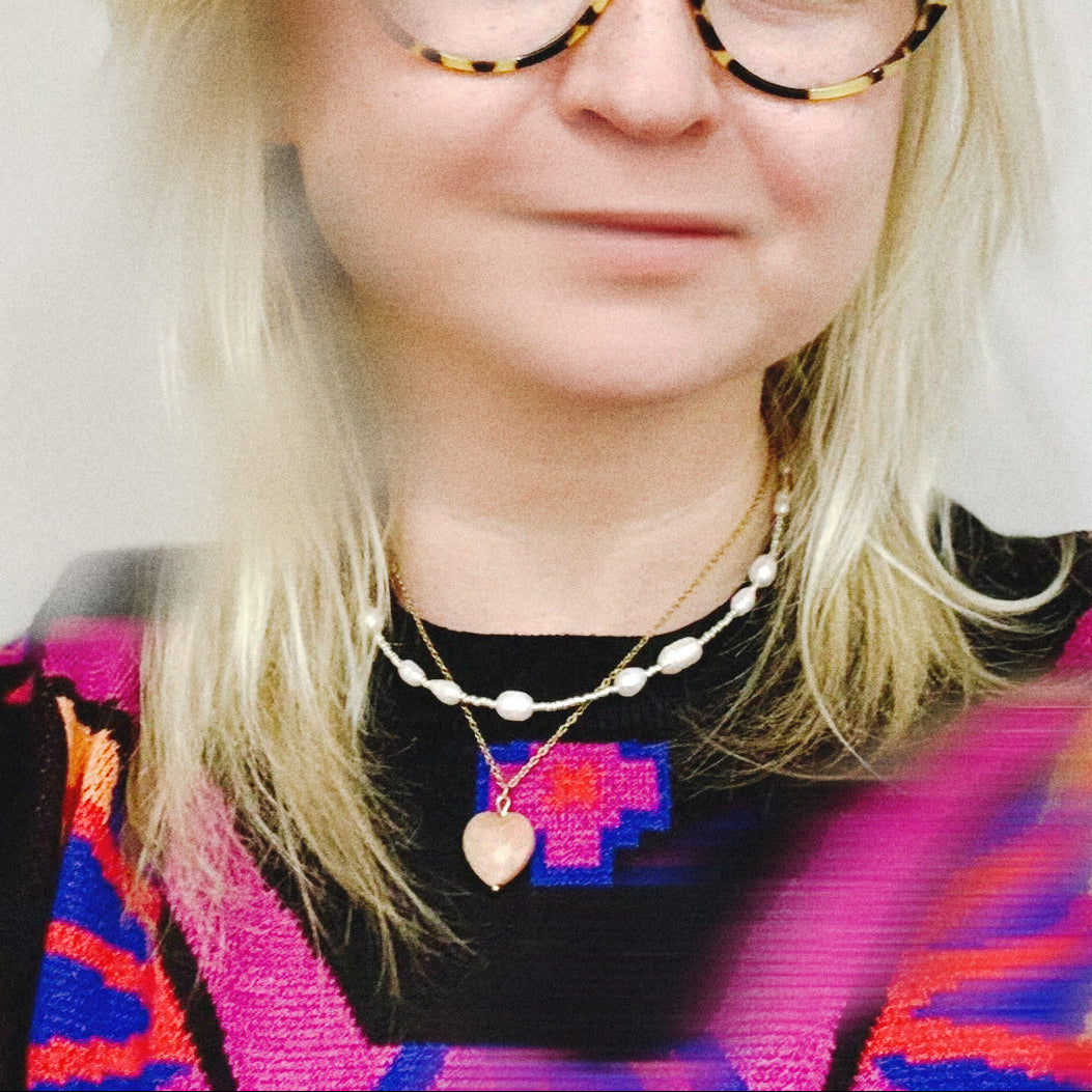 Person wearing colorful glasses and a multicolored sweater with a white background