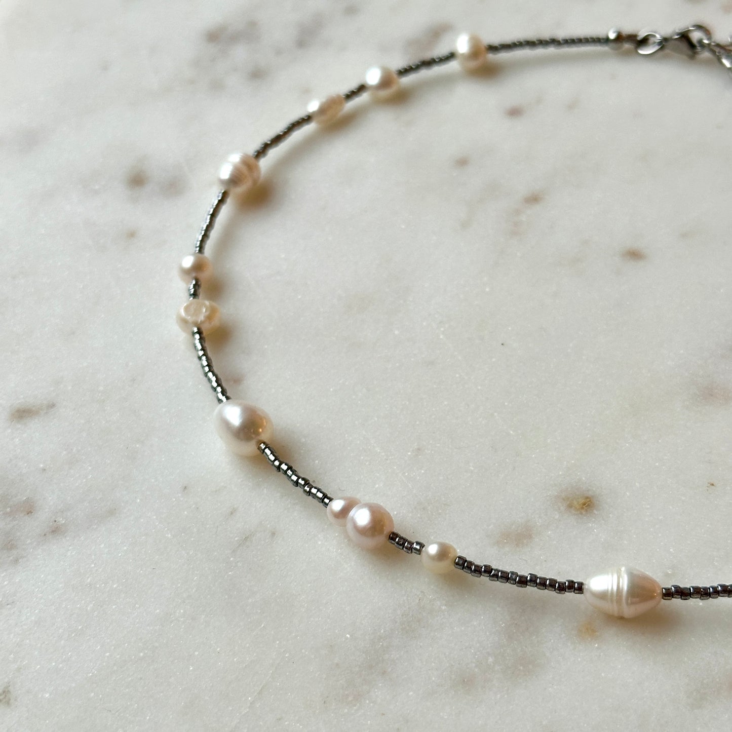 Necklace with pearls and black beads on a marble surface