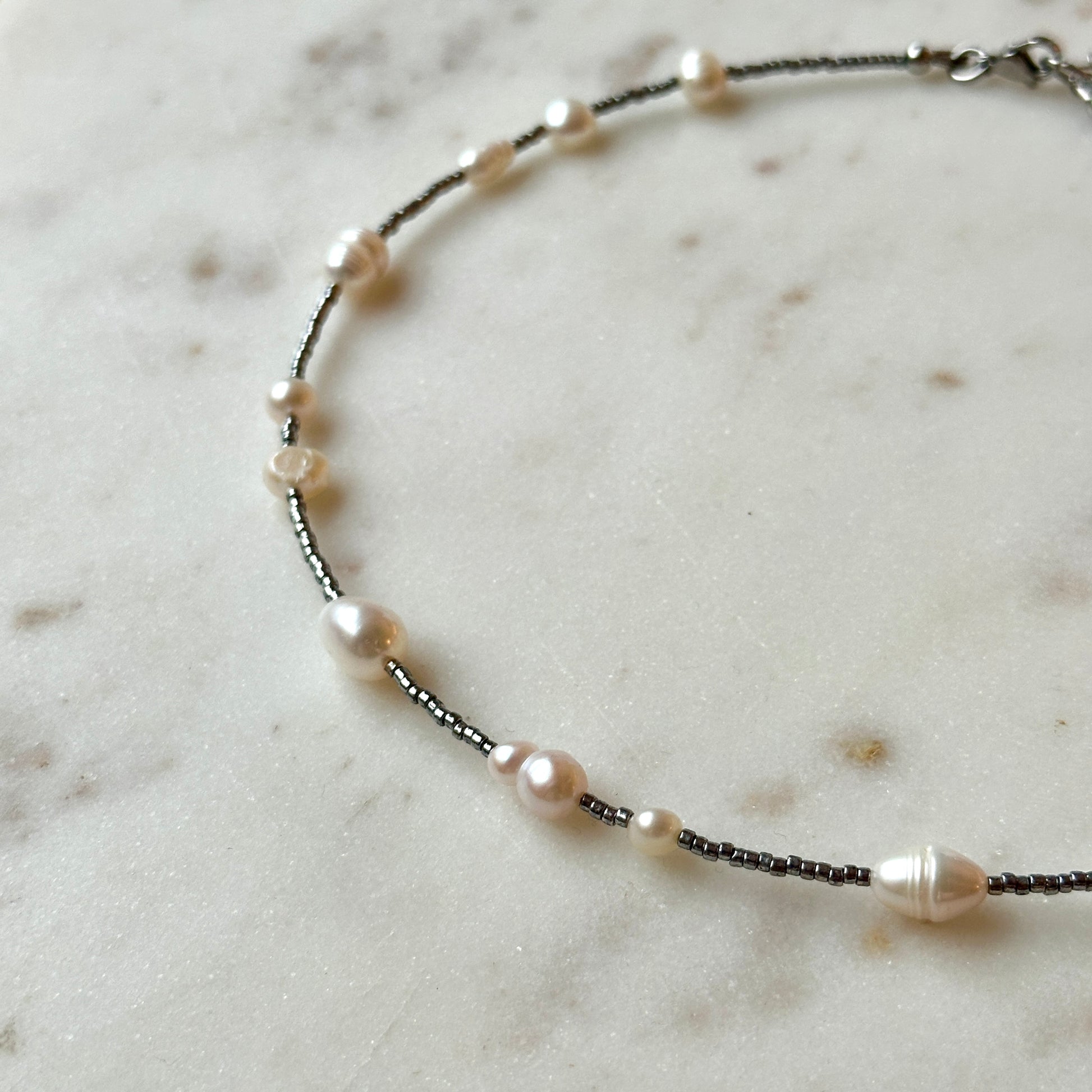 Necklace with pearls and black beads on a marble surface