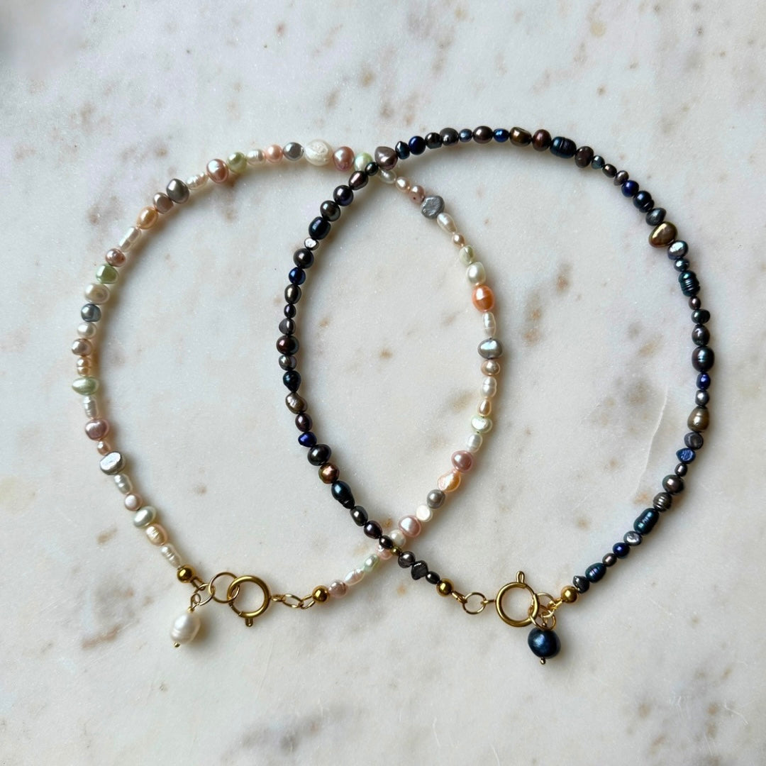 Two pearl necklaces on a marble surface