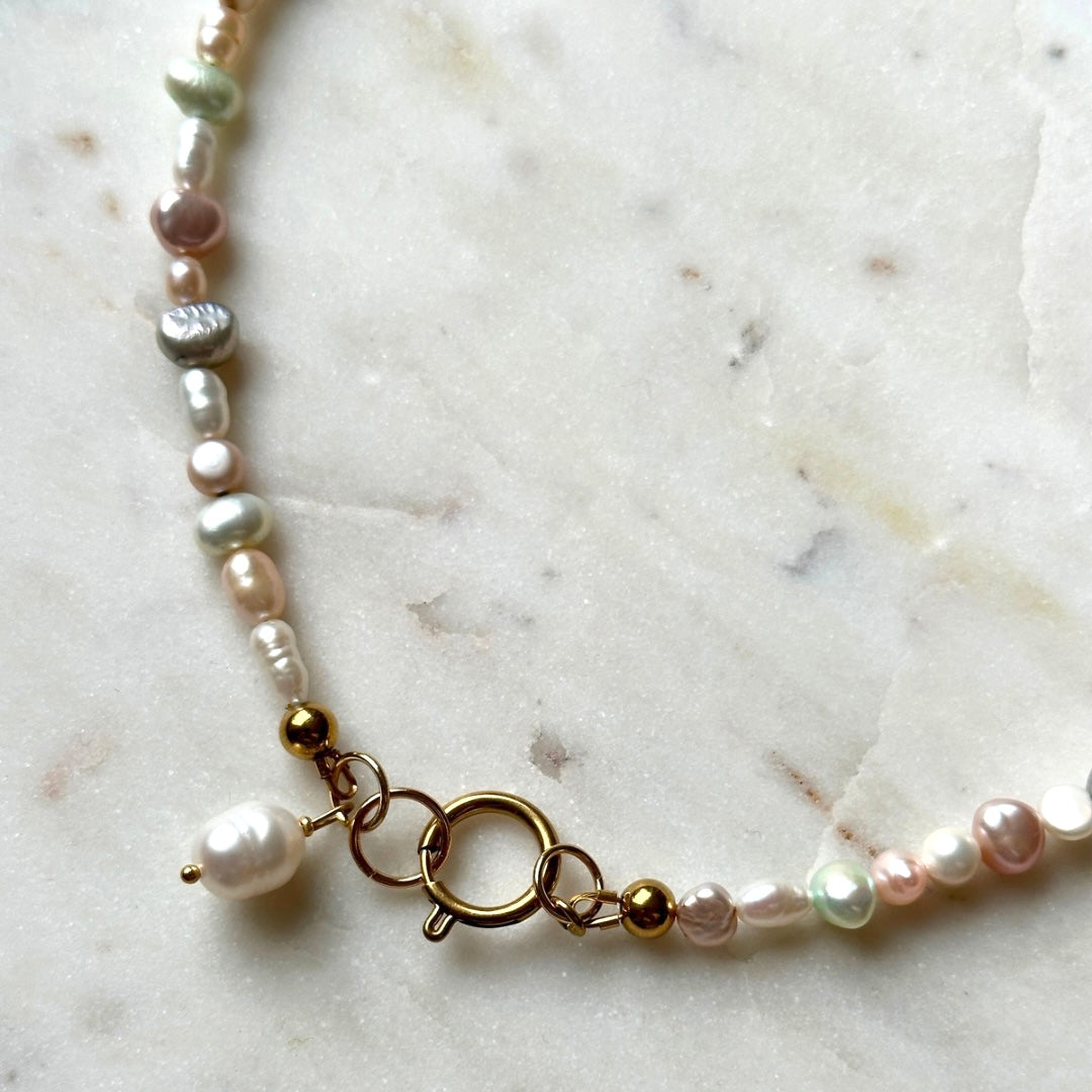 Pearl bracelet with gold accents on a marble surface