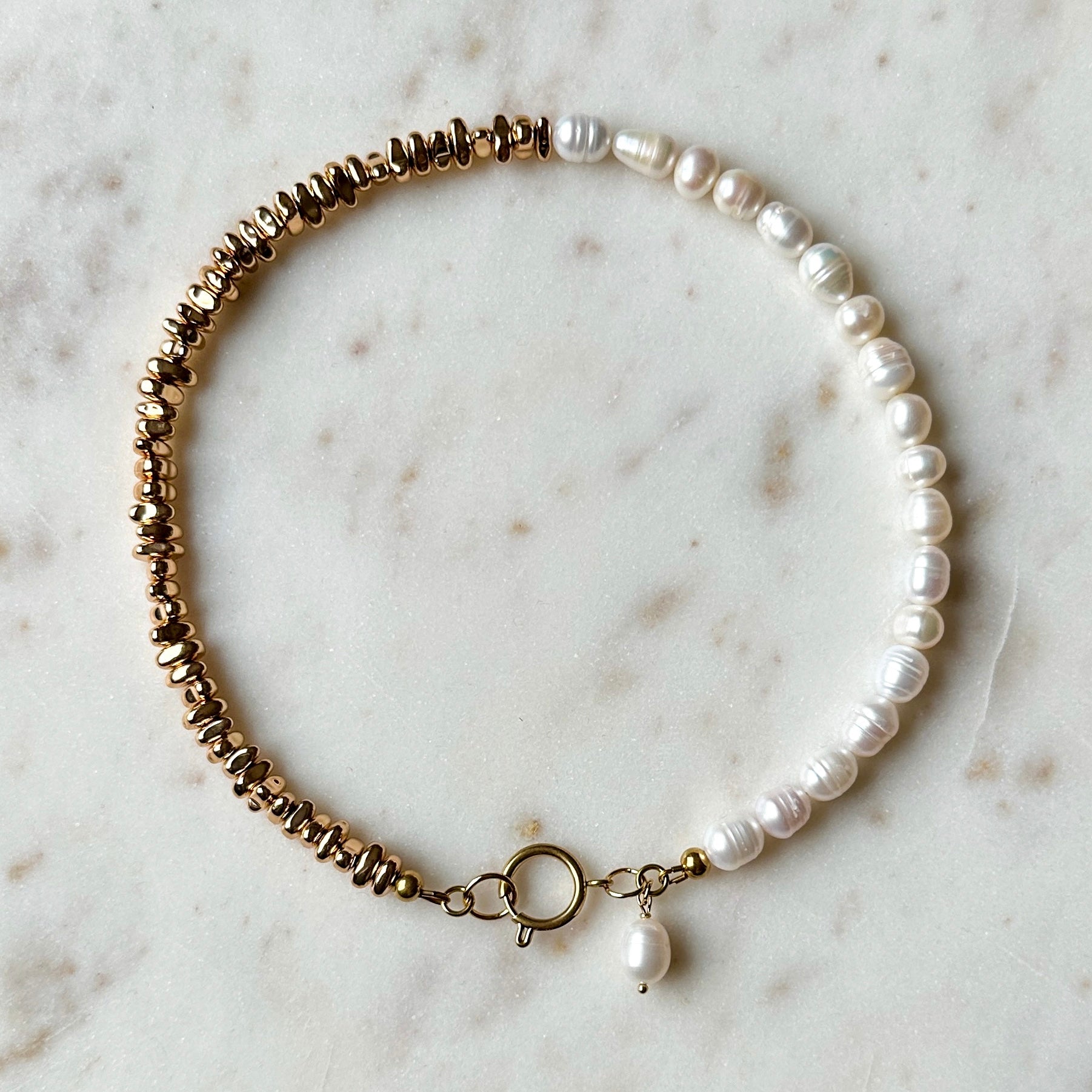 Pearl and gold hematite necklace on a marble surface