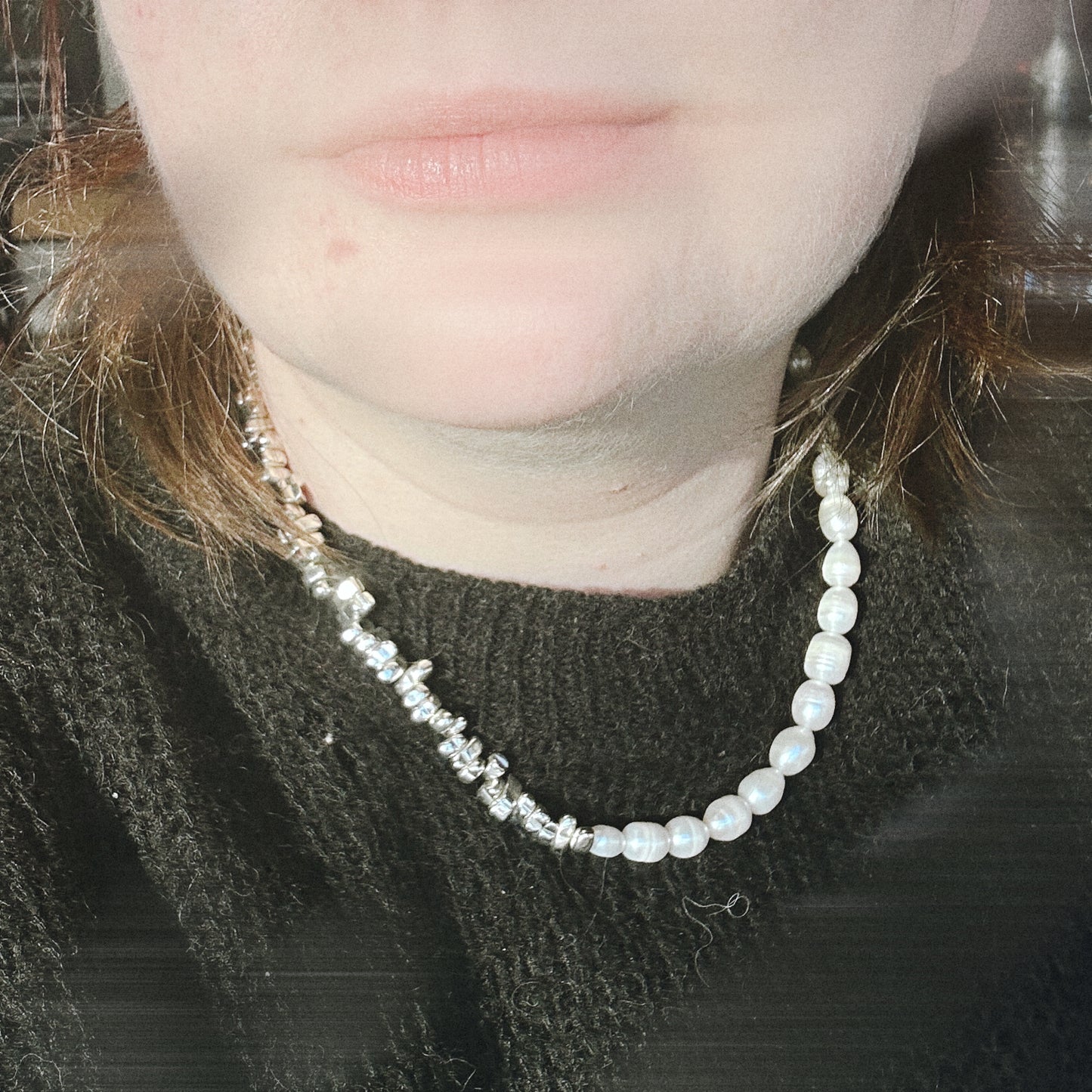 Close-up of a person wearing a pearl necklace with a blurred background