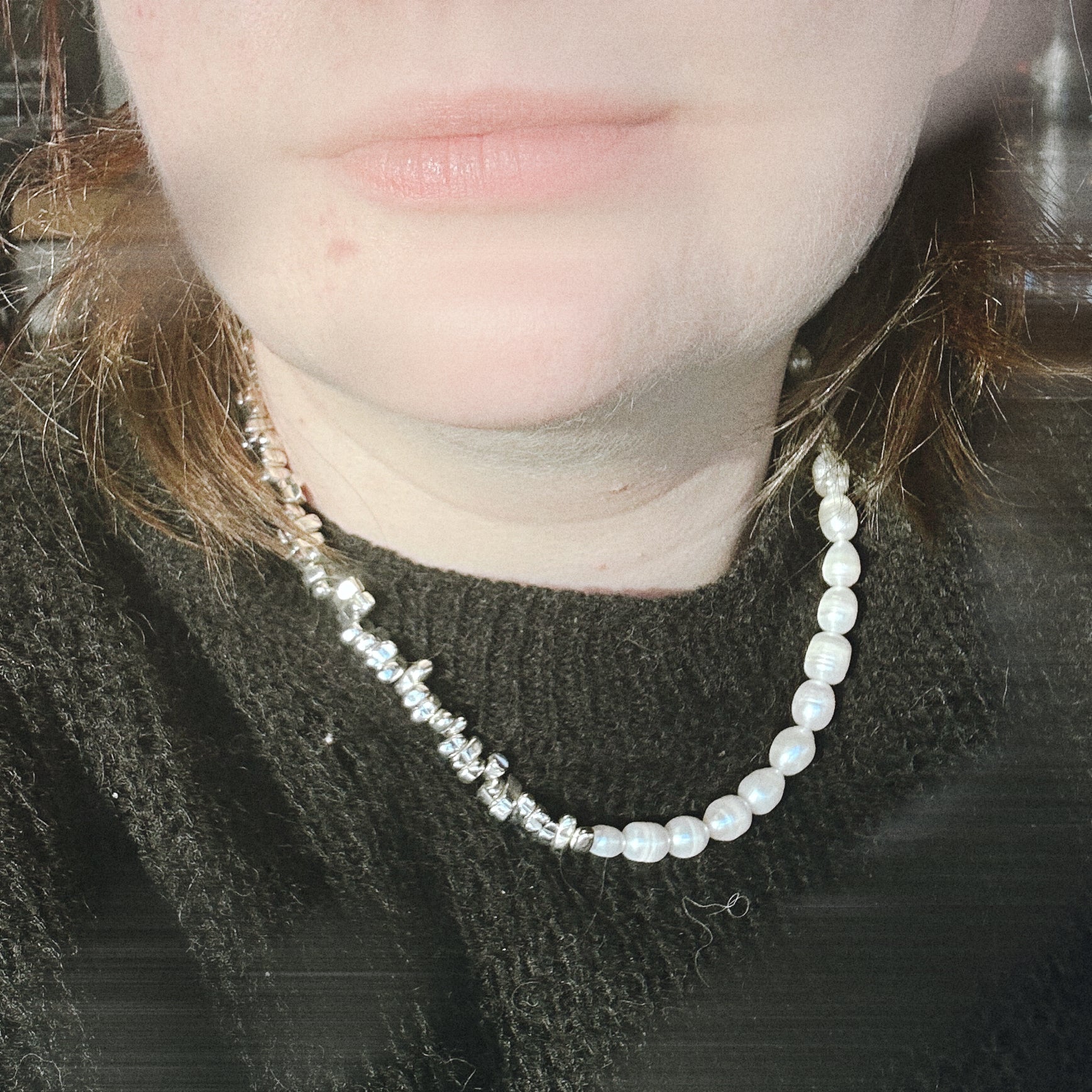 Close-up of a person wearing a pearl necklace with a blurred background