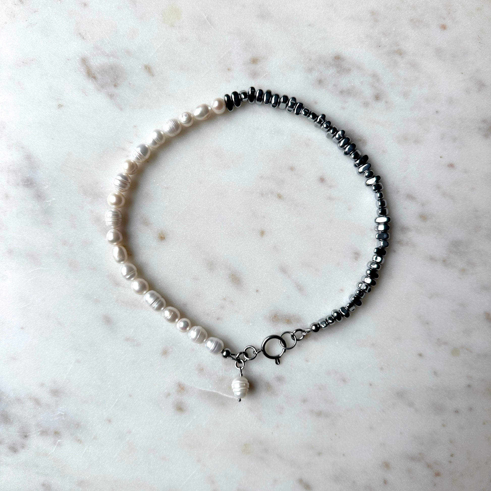 Handmade pearl necklace half with silver-plated hematite stones, and a hanging pearl pendant. 