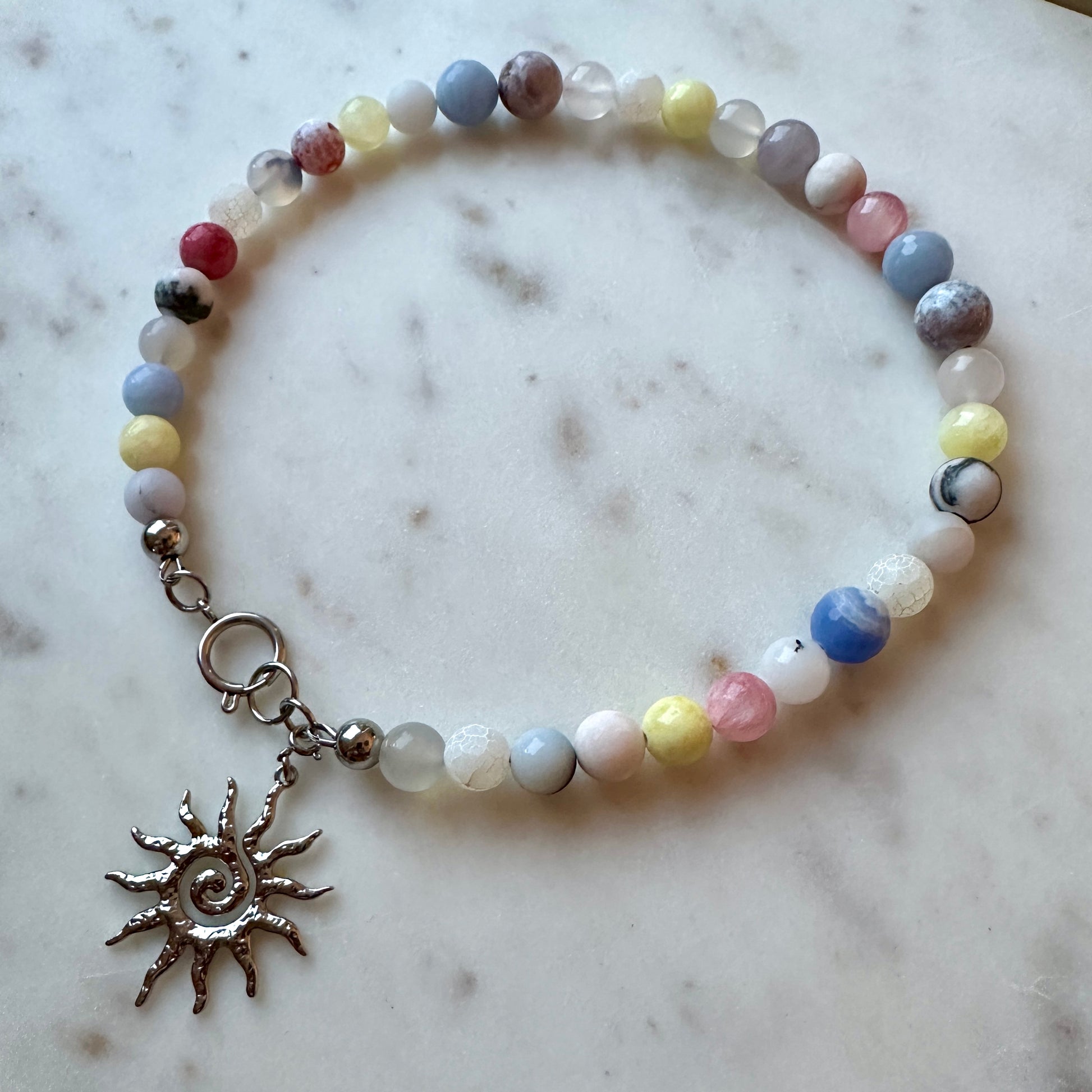 Beaded necklace with a sun charm on a marble surface