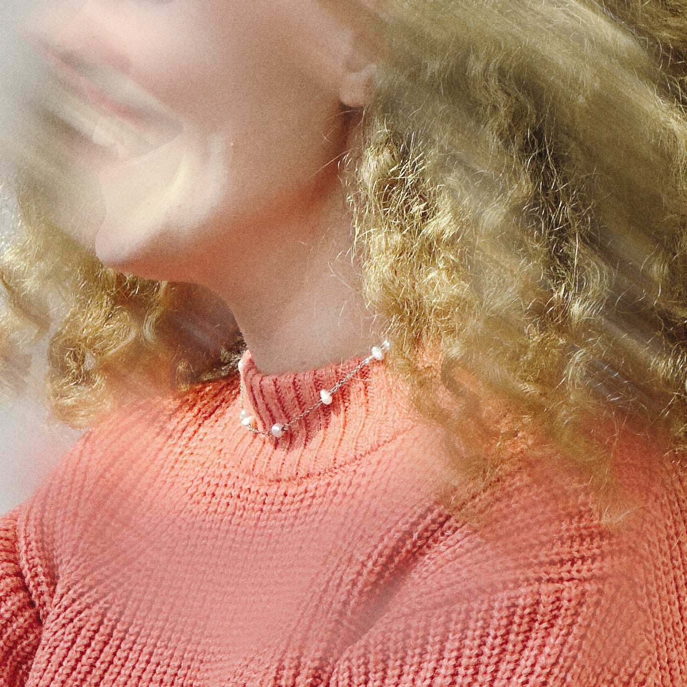 Close-up of a person wearing a pink knitted sweater with a blurred background